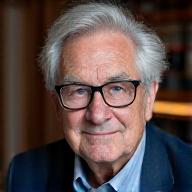 Portrait sérieux du Pr. Michel Bernard, homme âgé avec des lunettes et des cheveux gris, expert en psychanalyse.